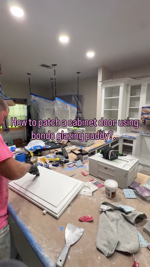 Painter filling a white shaker cabinet door with glazing putty during kitchen refinishing in Houston, TX