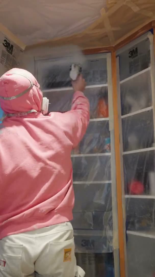 Crew spraying kitchen cabinets in a masked kitchen during refinishing in Houston, TX