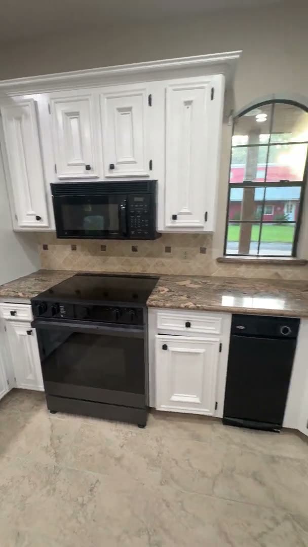 Finished white kitchen cabinets with granite counters and black appliances in Houston, TX